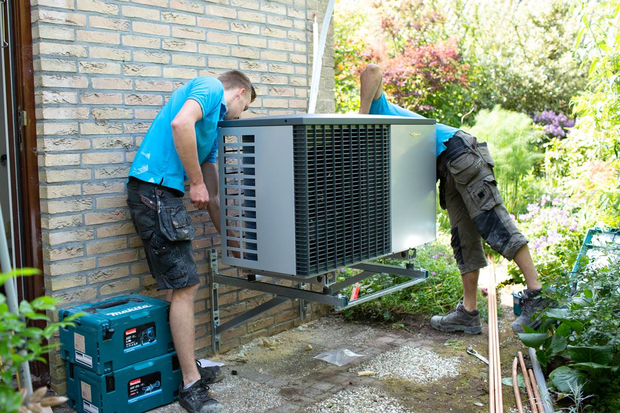 Twee mannen die een warmtepomp installeren